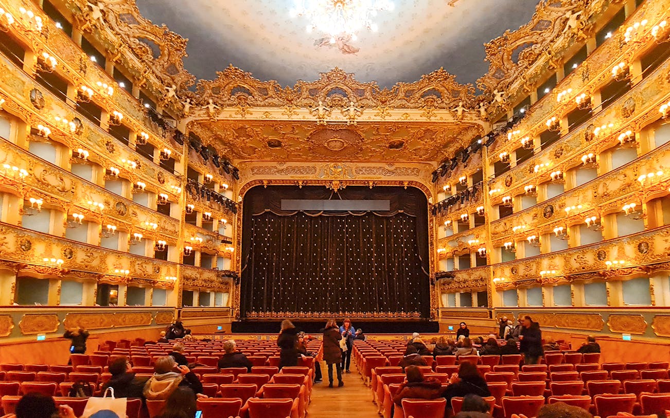 Teatro La Fenice interior with ornate balconies and stage curtain in Venice, Italy.