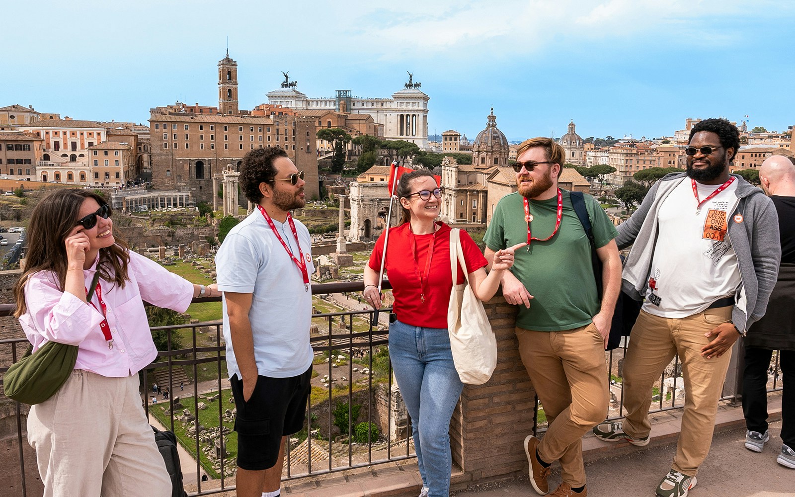 Tour group enjoying view of Roman Forum with Colosseum and Palatine Hill in background.