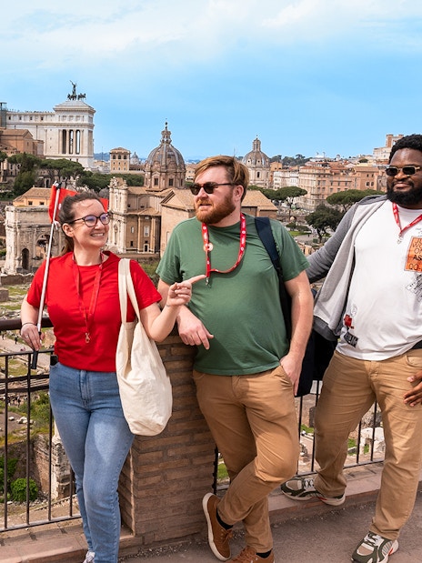 Tour group enjoying view of Roman Forum with Colosseum and Palatine Hill in background.