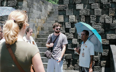 Tour guide with umbrella explaining Borobudur Temple to visitors.