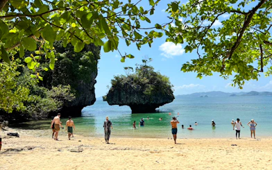 Tourists enjoying the beach and clear waters at Hong Island, Krabi, with limestone formations.