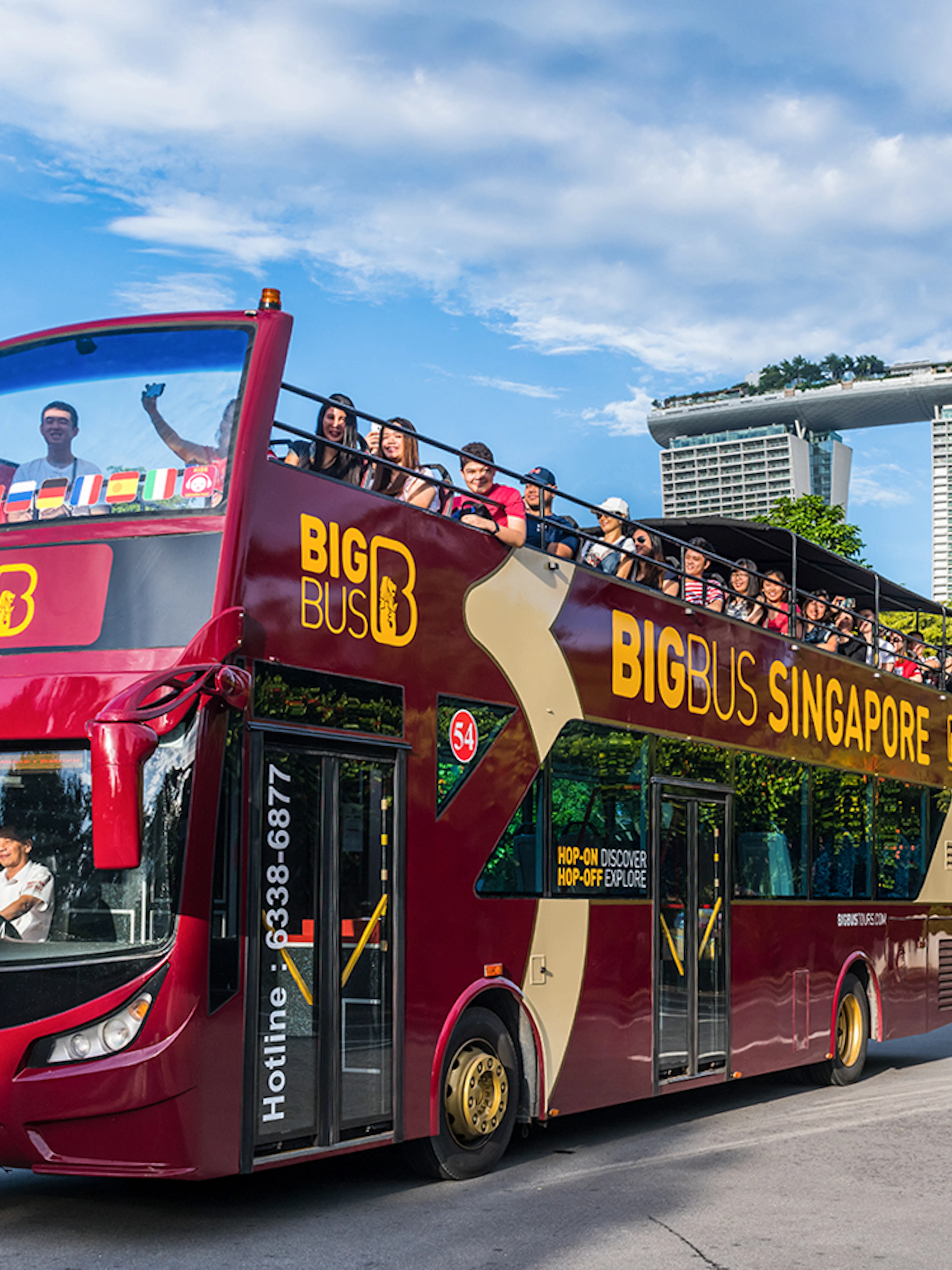 Tourists on a Singapore Hop-On-Hop-Off bus with Marina Bay Sands in the background.