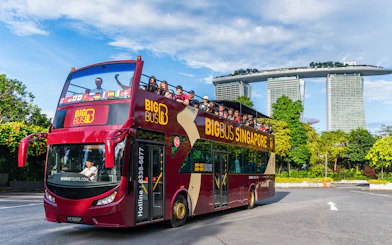 Tourists on a Singapore Hop-On-Hop-Off bus with Marina Bay Sands in the background.