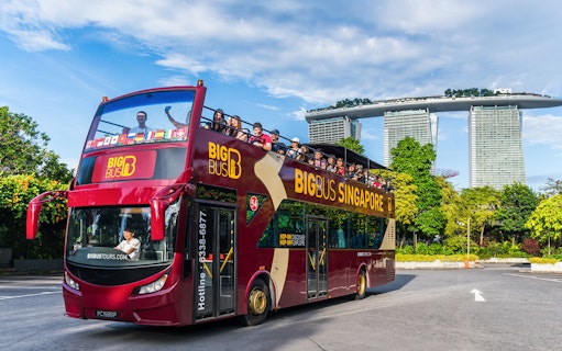 Tourists on a Singapore Hop-On-Hop-Off bus with Marina Bay Sands in the background.