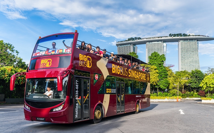 Tourists on a Singapore Hop-On-Hop-Off bus with Marina Bay Sands in the background.