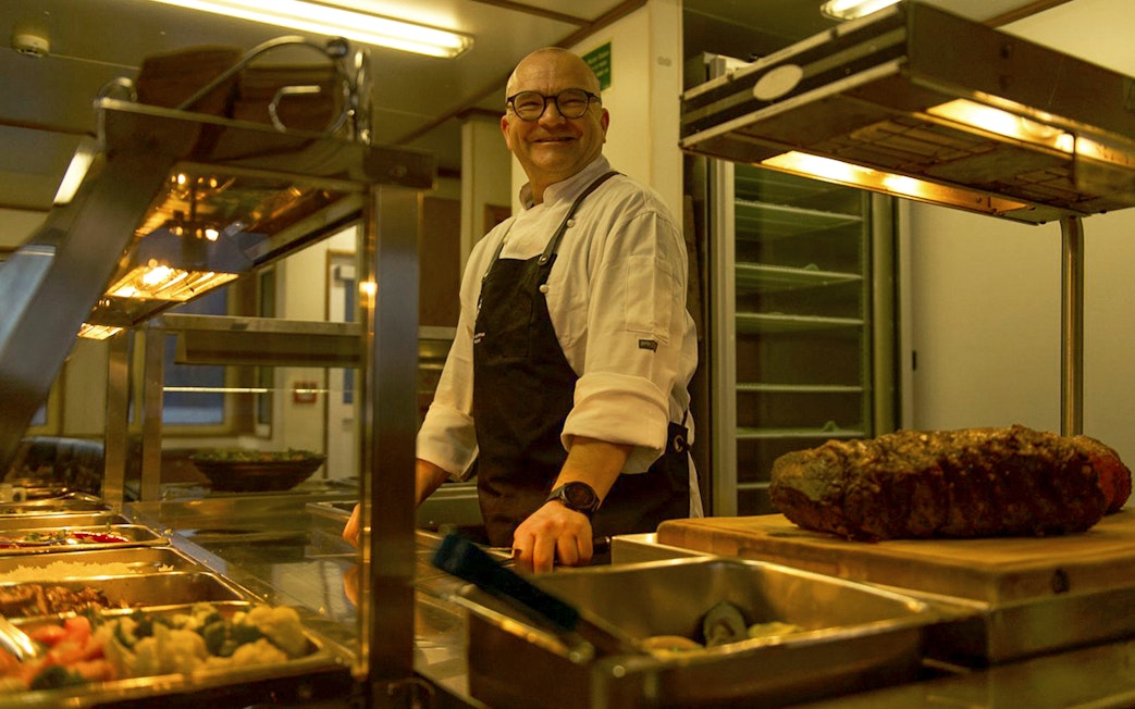 Chef preparing buffet on cruise ship during Te Anau overnight tour.