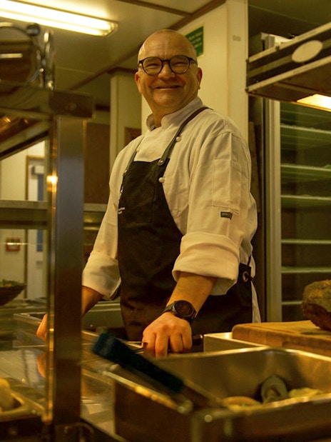 Chef preparing buffet on cruise ship during Te Anau overnight tour.