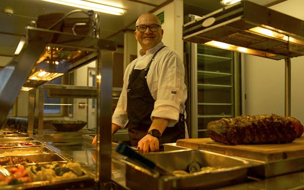 Chef preparing buffet on cruise ship during Te Anau overnight tour.
