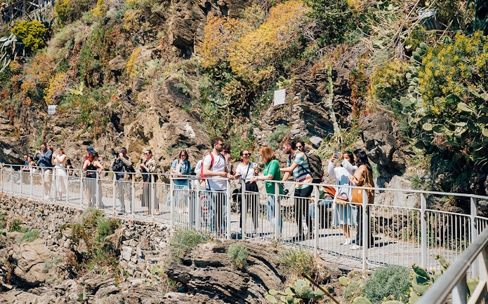 Tourists walking along a scenic cliffside path in Cinque Terre, Italy.