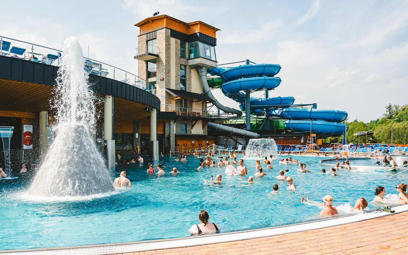 Outdoor pool with people enjoying water slides at a Zakopane resort during a day trip from Krakow.