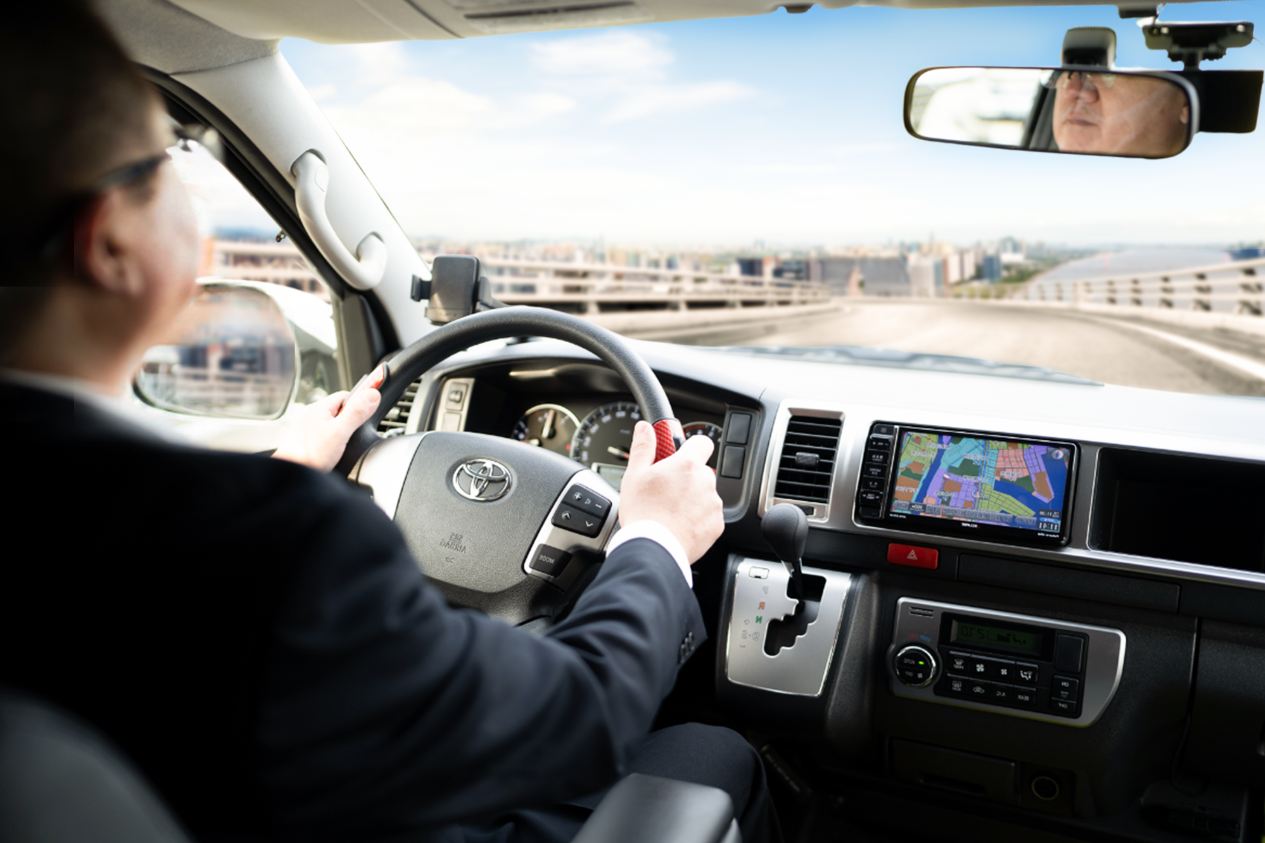 Kansai Airport shuttle van driver navigating with GPS towards hotel drop-off.