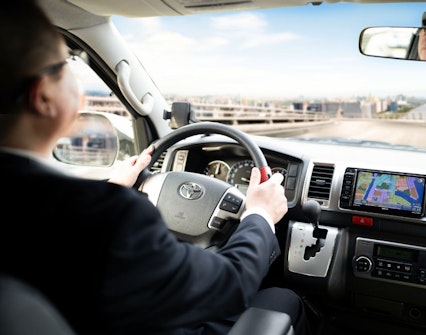 Kansai Airport shuttle van driver navigating with GPS towards hotel drop-off.