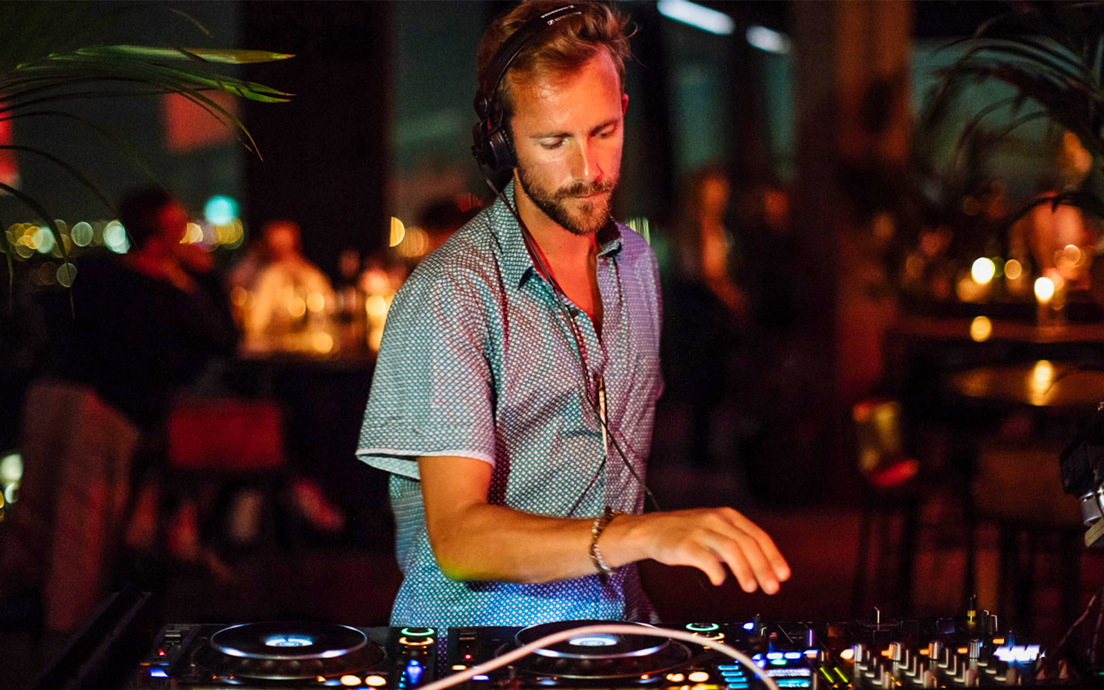 DJ performing at ADAM Lookout in Amsterdam with city skyline in the background.
