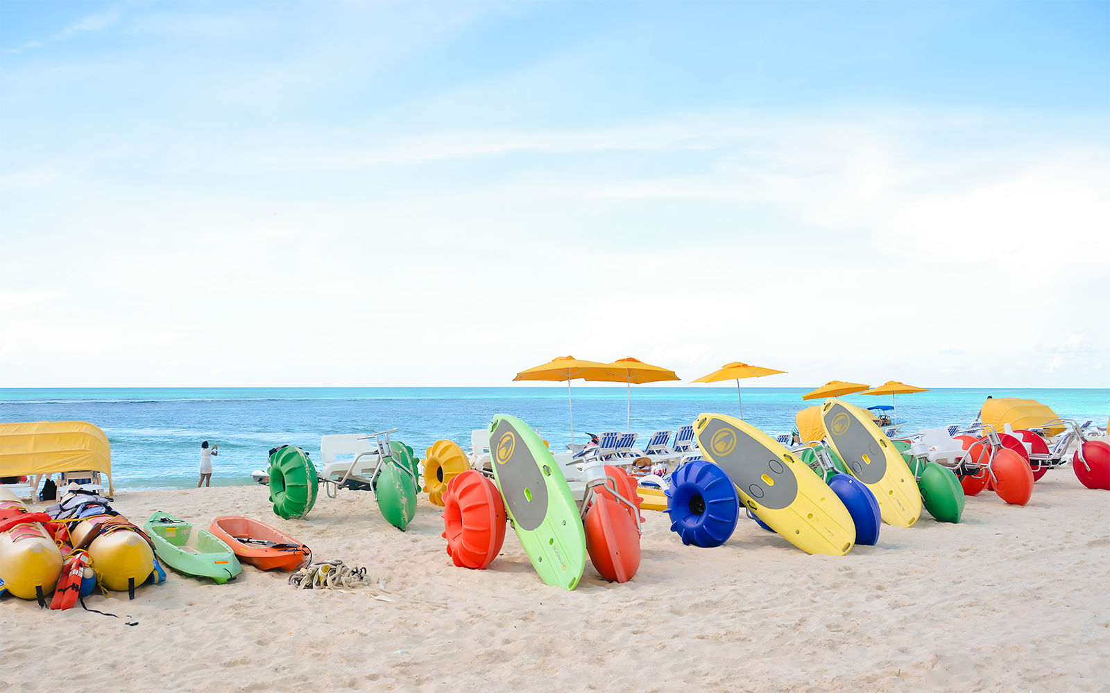 Colorful kayaks and water bikes on a sandy beach in Bimini, Bahamas.