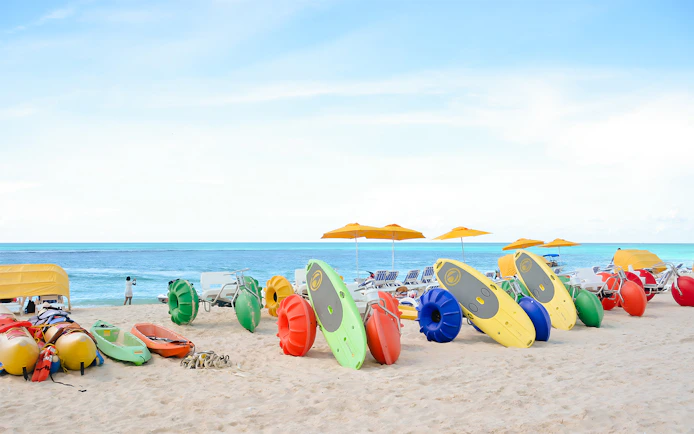 Colorful kayaks and water bikes on a sandy beach in Bimini, Bahamas.