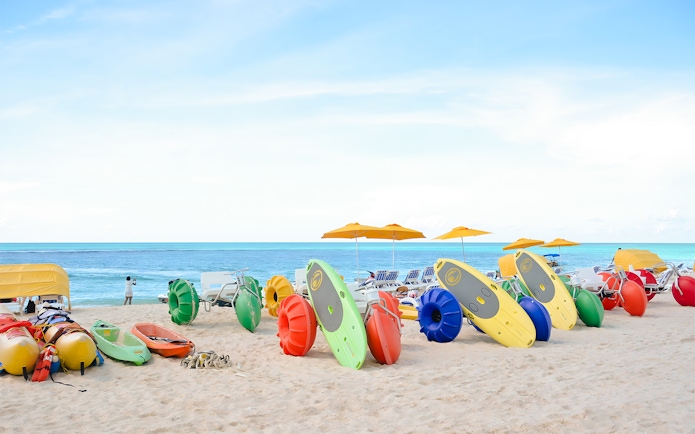 Colorful kayaks and water bikes on a sandy beach in Bimini, Bahamas.