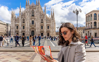 Woman reading City Sightseeing map in front of Milan Cathedral.