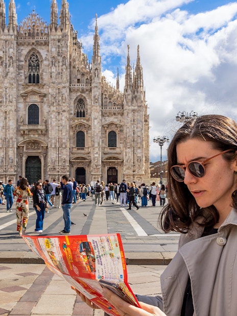 Woman reading City Sightseeing map in front of Milan Cathedral.