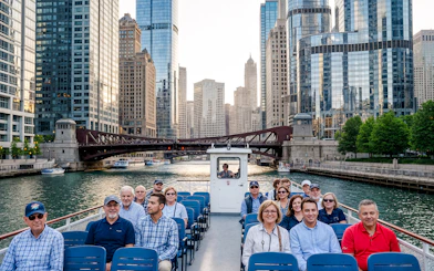 Boat tour on Chicago River with group, surrounded by modern skyscrapers and bridges.