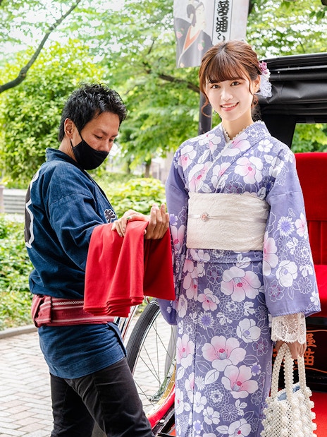 Rickshaw ride in Japan with woman in kimono and guide assisting.