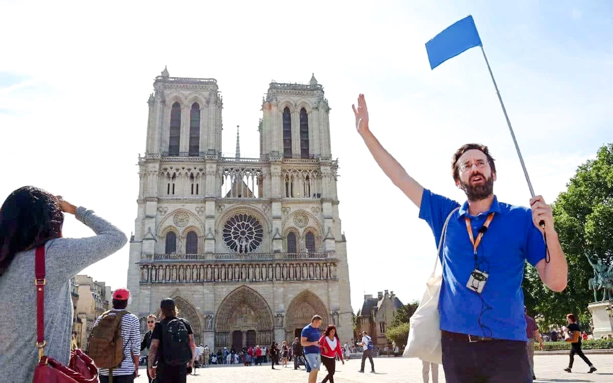 Guide leading a tour in front of Notre Dame Cathedral, Paris, France.