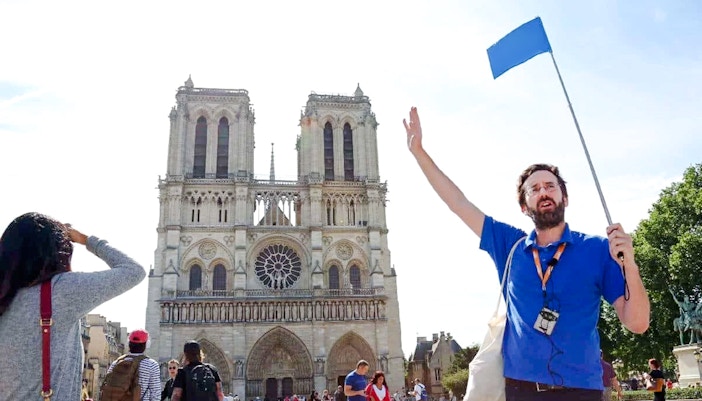 Guide leading a tour in front of Notre Dame Cathedral, Paris, France.