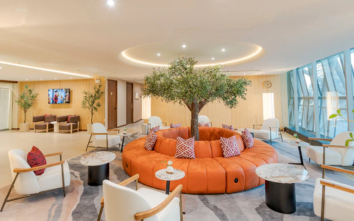 Coral Airport Lounge seating area with tree centerpiece at Suvarnabhumi Airport.