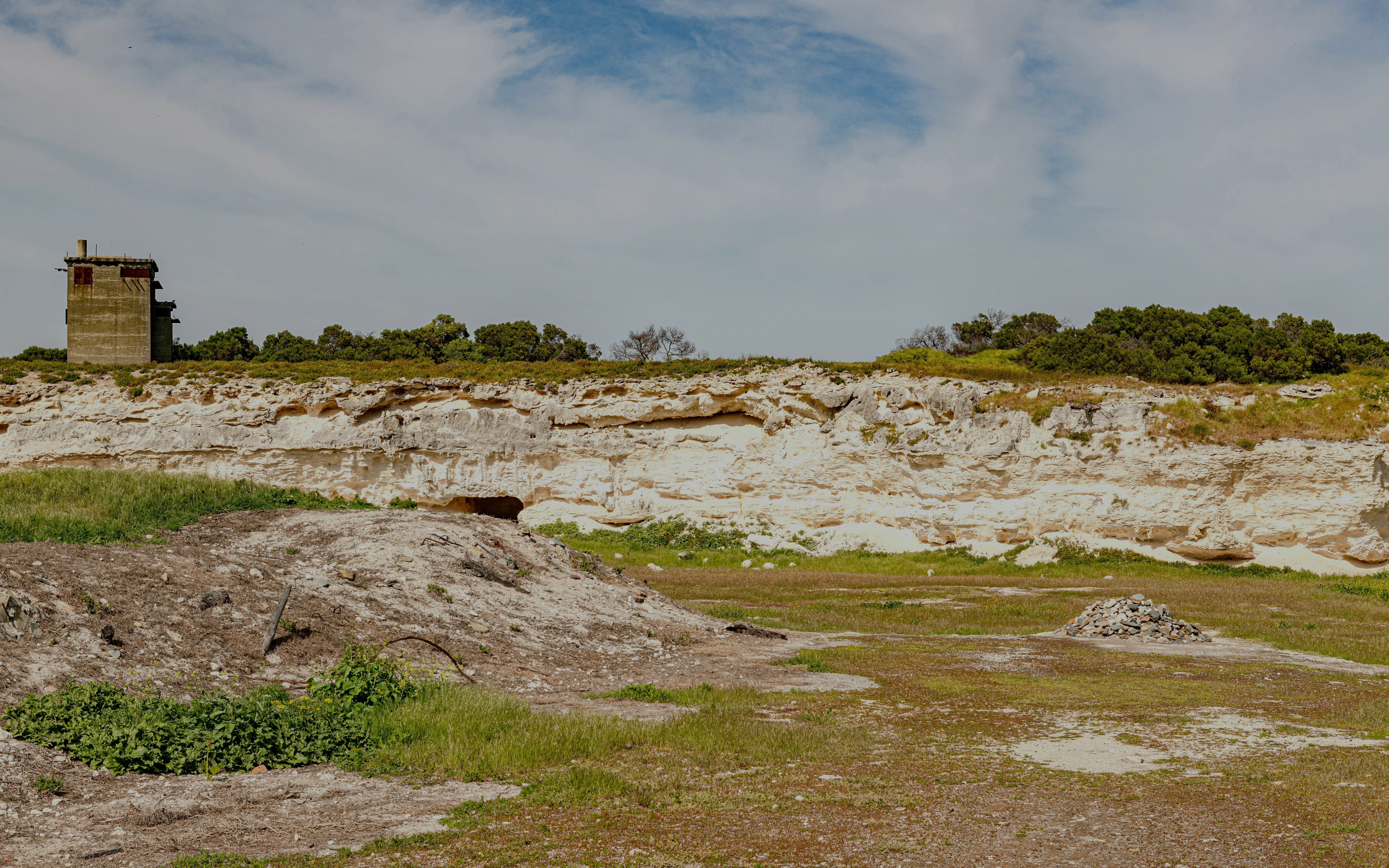 Quarry at Robben Island Prison with stone pile and greenery, Cape Town, South Africa.