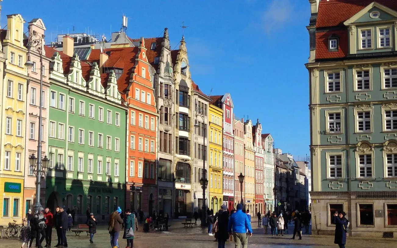 Colorful historic buildings in Wroclaw's Old Town, Poland, with people exploring the square.