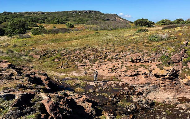 Trekker on rocky Tonnare Trail landscape near Gonnesa, Sardinia.