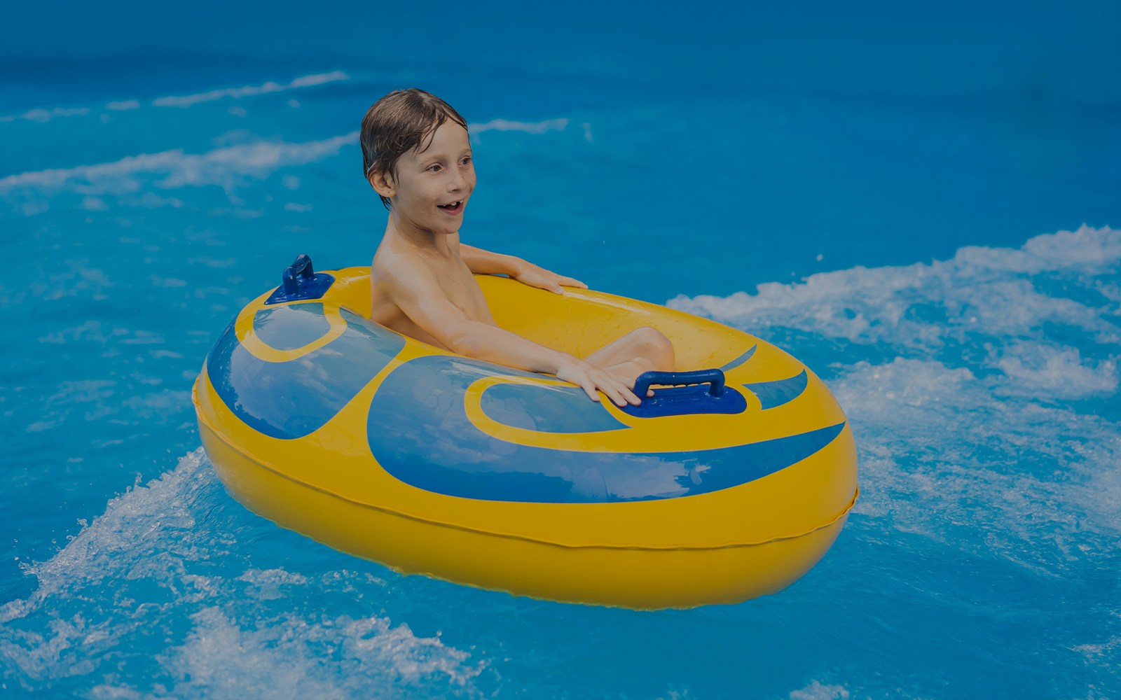 Child enjoying wave pool in inflatable tube at Aqualand waterpark.