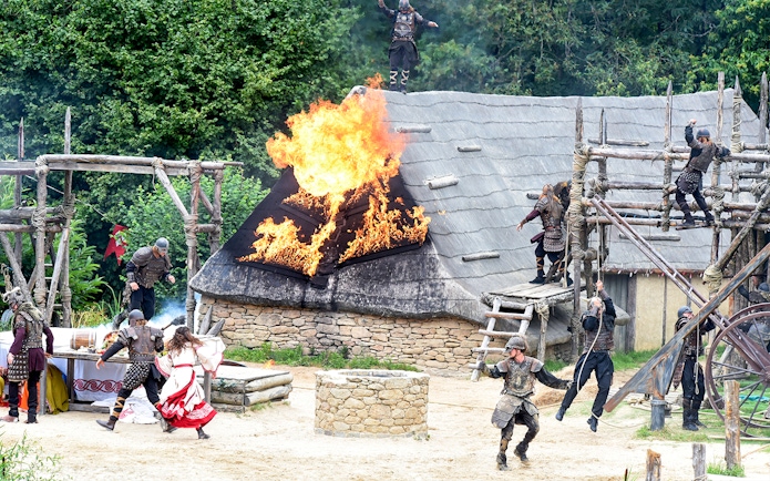 Viking reenactment with actors and burning roof at Puy du Fou, France.