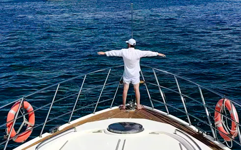 Person standing on yacht deck with arms outstretched, Sanya Phoenix Island tour.