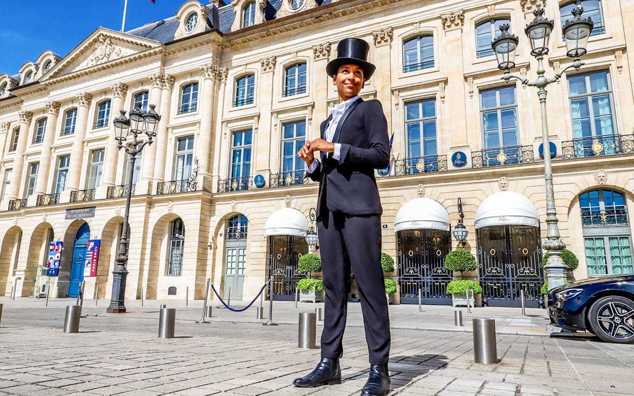 Person in a top hat standing in front of a historic Parisian building on Josephine Baker's Paris tour.