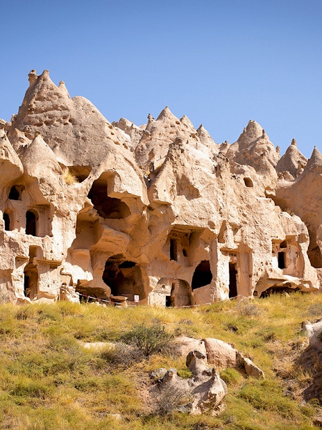 Ancient rock formations and cave dwellings in Cappadocia, Turkey, under a clear blue sky.