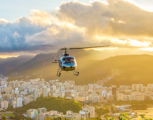 Helicopter taking off from Urca mountain helipad at sunset, Rio de Janeiro, Brazil.