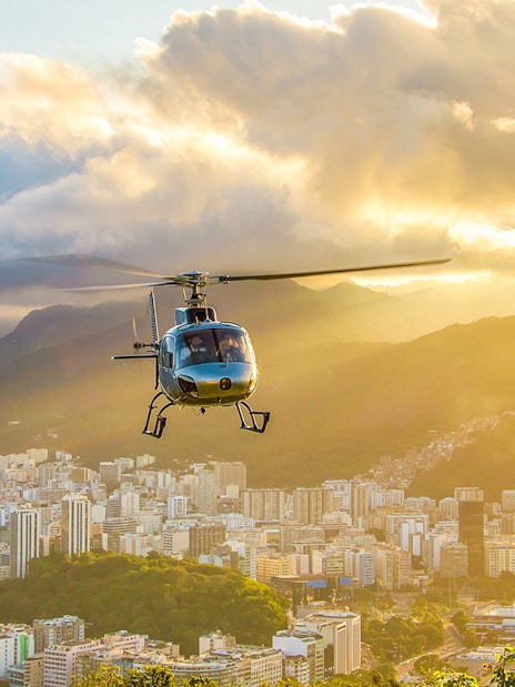 Helicopter taking off from Urca mountain helipad at sunset, overlooking Rio de Janeiro, Brazil.
