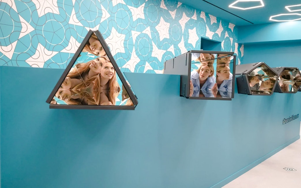 Visitors interacting with mirrored installations in the Kaleidoscope room at Paradox Museum Paris.