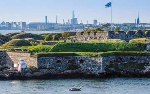 Suomenlinna Sea Fortress with visitors and Finnish flag, Helsinki, Finland.