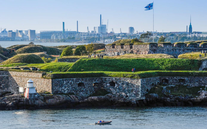 Suomenlinna Sea Fortress with visitors and Finnish flag, Helsinki, Finland.