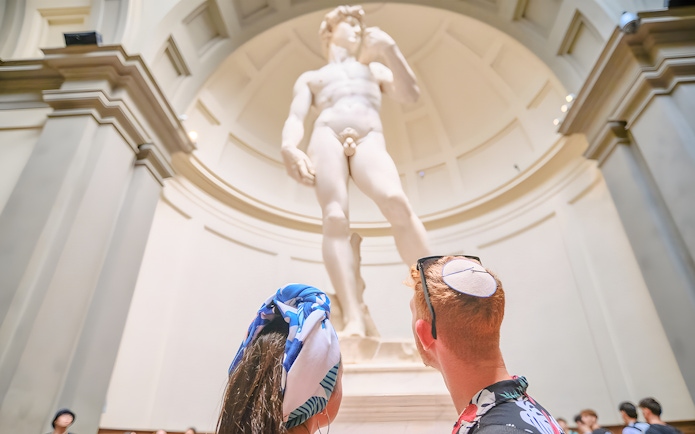 Couple admiring Michelangelo's David at Accademia Gallery, Florence.