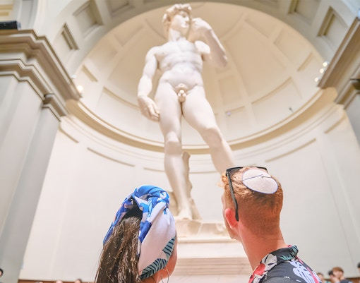 Couple admiring Michelangelo's David sculpture at Accademia Gallery, Florence.