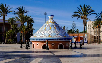 Decorative tagine sculpture in a plaza with palm trees, Safi, Morocco.