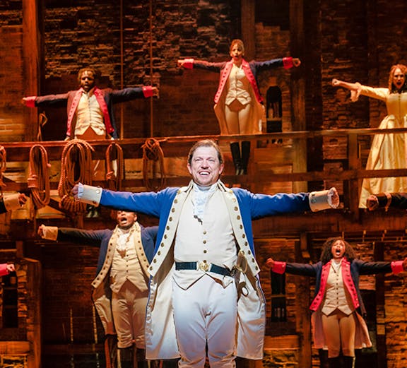 Stage performance of historical musical with actors in period costumes, "True Story" theme.