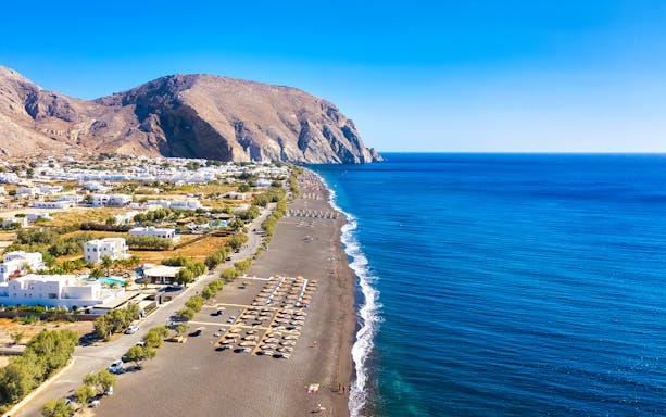 Santorini coastline with black sand beach and Aegean Sea, part of semi-private city tour.