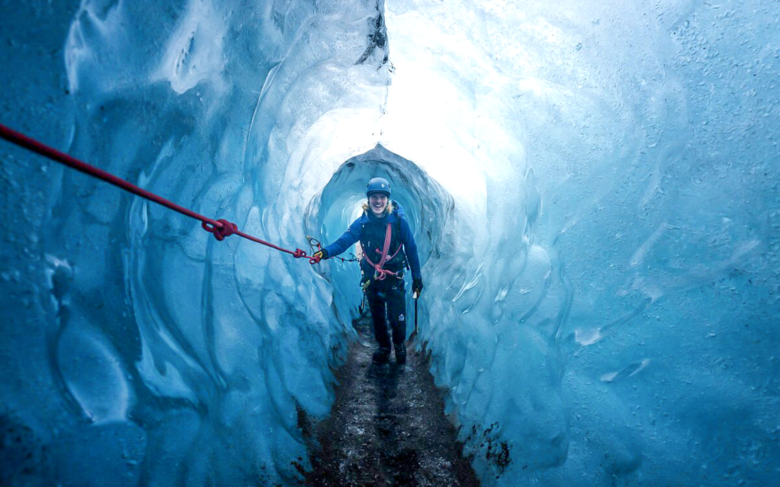 Guests hiking inside Blue Ice Cave in Vatnajökull, Iceland, holding a safety rope.