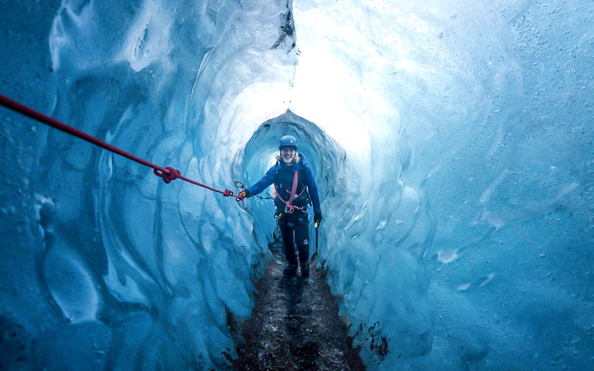 Guests hiking inside Blue Ice Cave in Vatnajökull, Iceland, holding a safety rope.