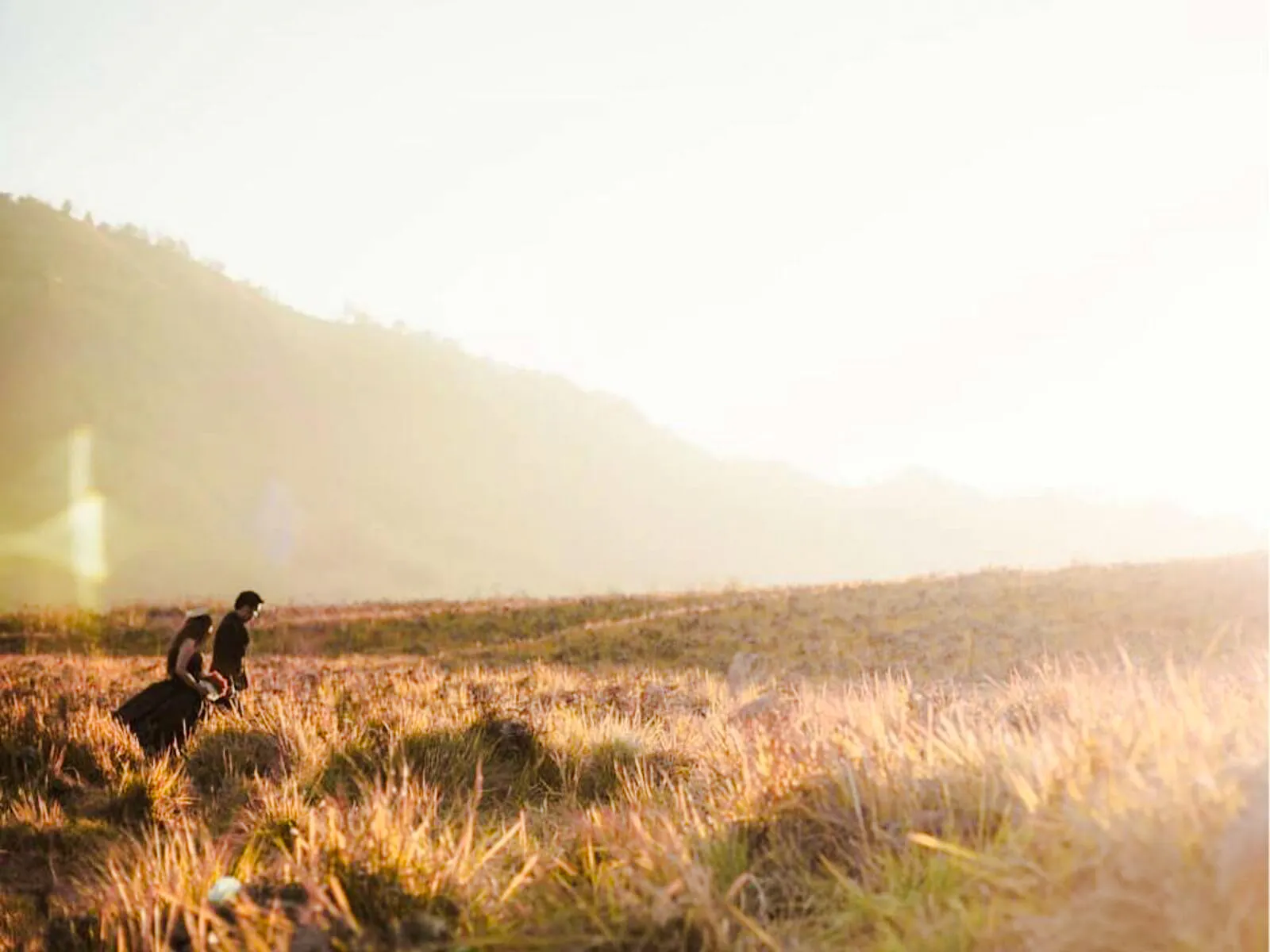 Couple walking through grassy field during sunset in Lombok.
