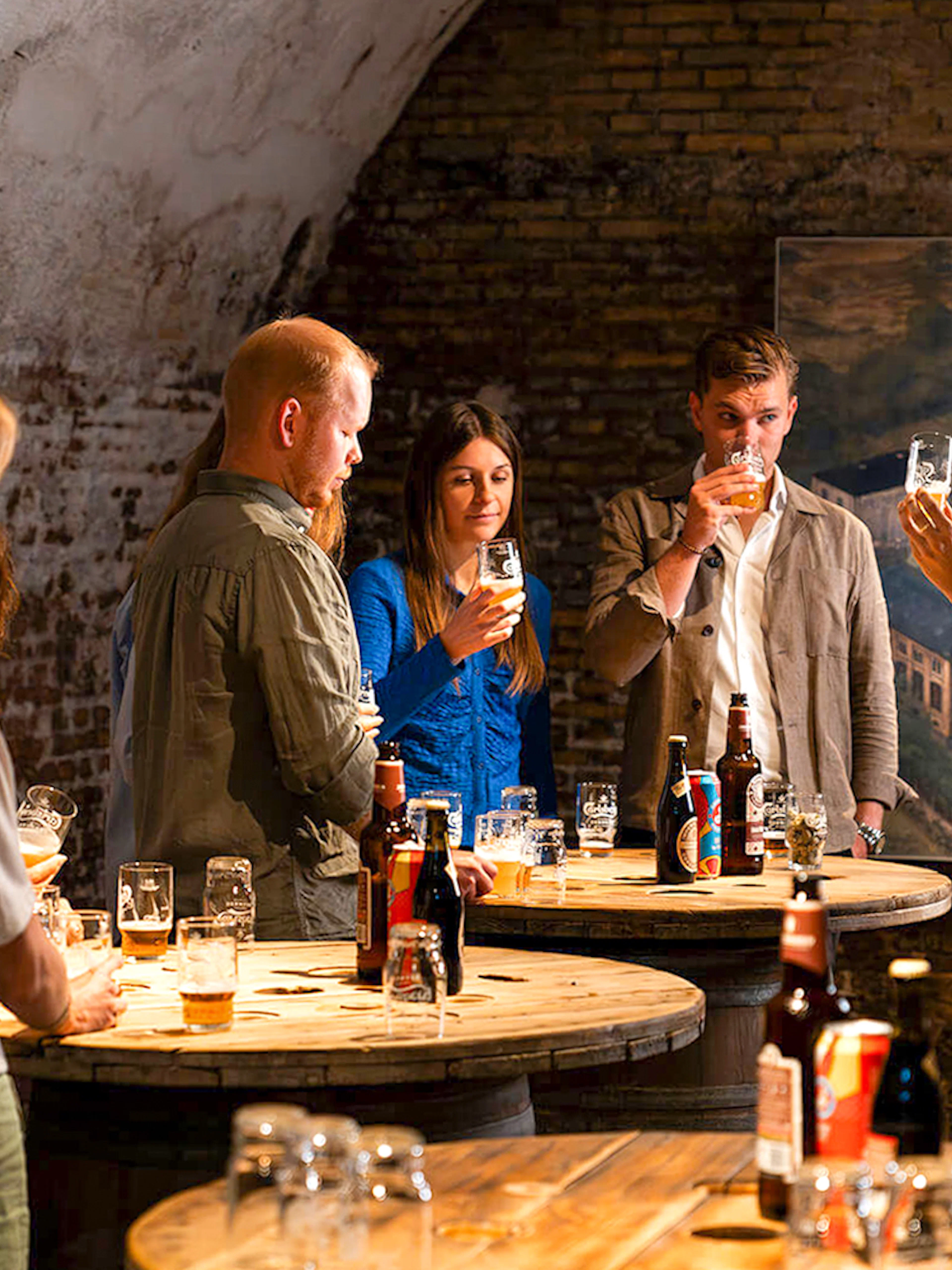 Guests participating in a beer tasting session in a rustic cellar setting.