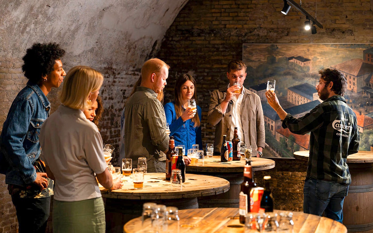 Guests participating in a beer tasting session in a rustic cellar setting.